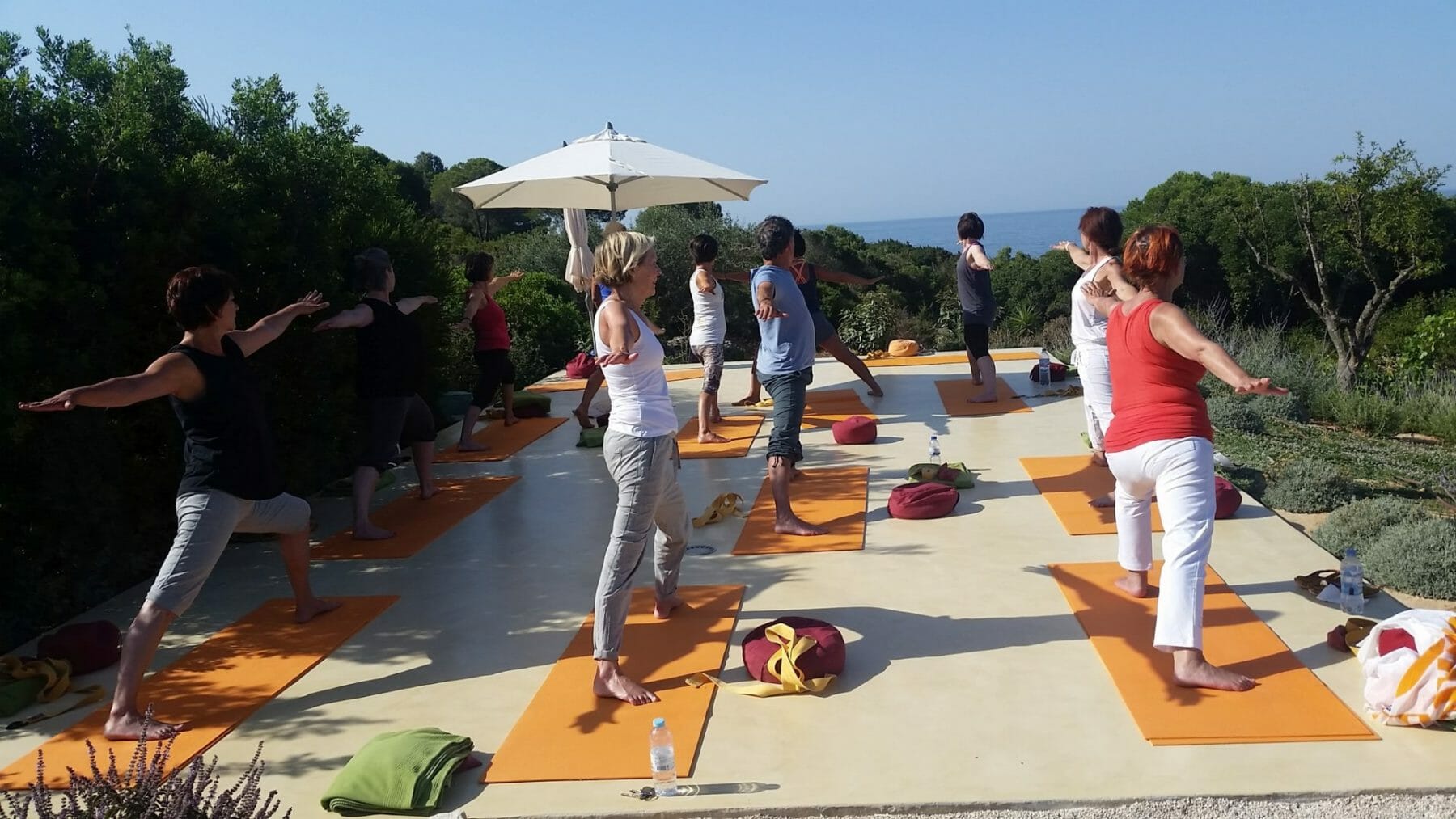 Yoga Retreat - Gruppe auf Yogaplattform im Sommer mit Blick aufs Meer Yoga Retreat - Gruppe auf Yogaplattform im Sommer mit Blick aufs Meer