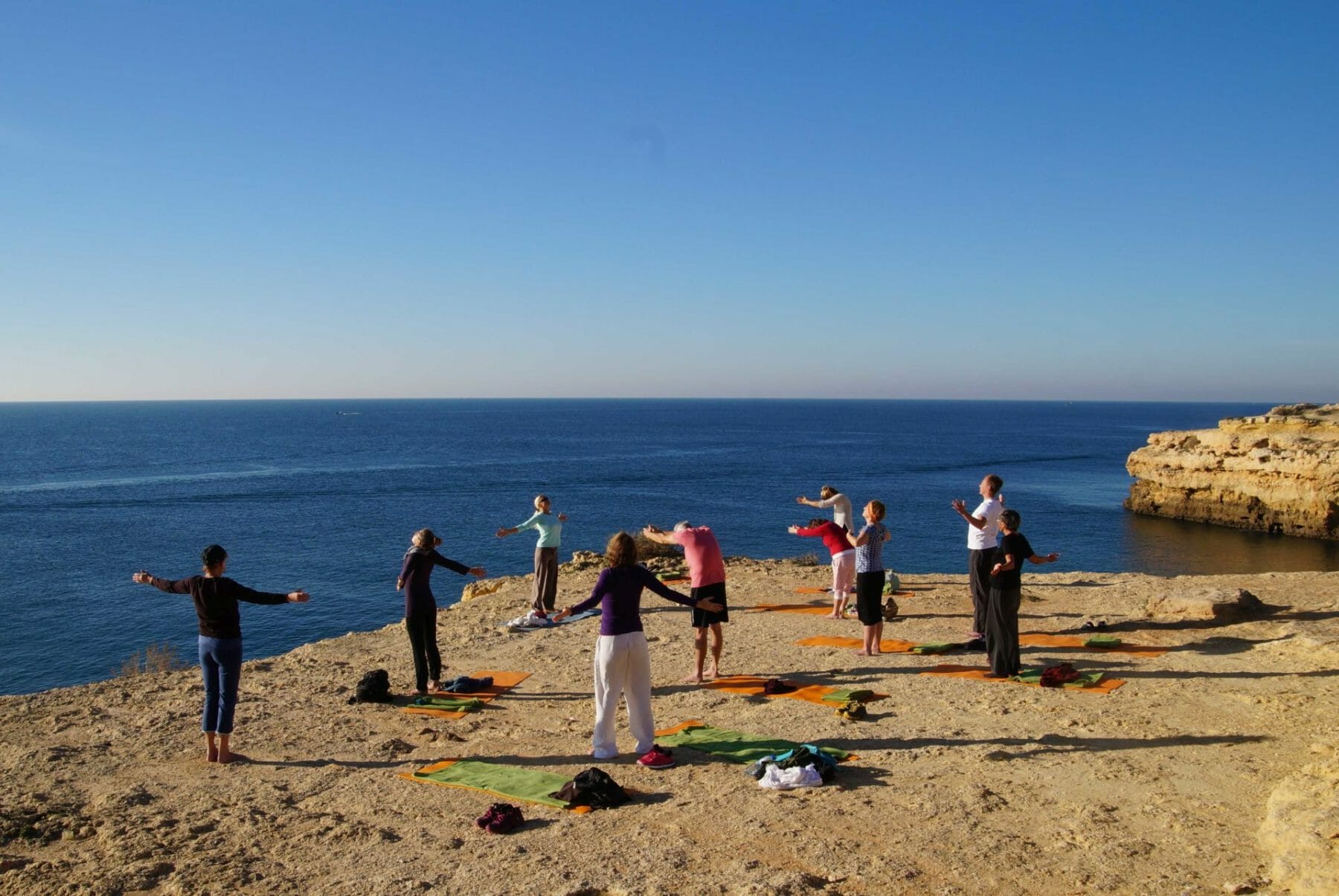 Yogagruppe am Meer auf Klippe über dem Atlantik