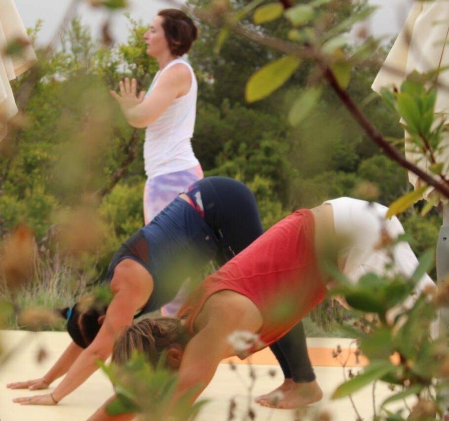 Yoga Retreat - Gruppe auf Yogaplattform im Sommer mit Blick aufs Meer 