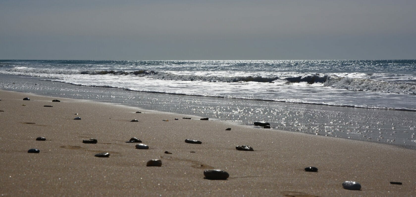 Steine auf Sandstrand am Meer Steine auf Sandstrand am Meer